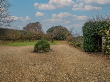 A gravel path branching into two directions with bushes and trees on each side at The Coach House in Gilwern near Crickhowell and Abergavenny