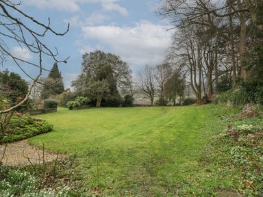 A garden with a lawn surrounded by trees and shrubs at The Coach House in Gilwern near Crickhowell and Abergavenny