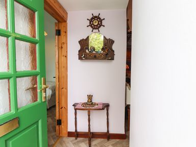 A hallway with a wooden table and a mirror with nautical decorations at Brendan's Cottage in Valentia Island County Kerry