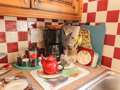A kitchen countertop with a red teapot jars utensils cutting boards and a coffee maker at Brendans Cottage Valentia Island County Kerry