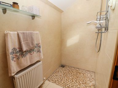 A tiled walk-in shower with a showerhead and towel rack with towels at Brendans Cottage in Valentia Island County Kerry