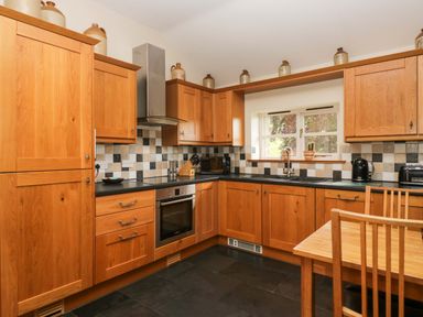 A kitchen with wooden cabinets and appliances at Copper Beech Cottage in Torver