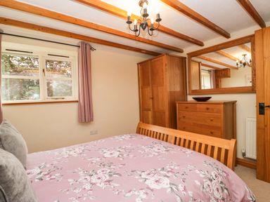 A bedroom with a bed and wardrobe at Copper Beech Cottage in Torver