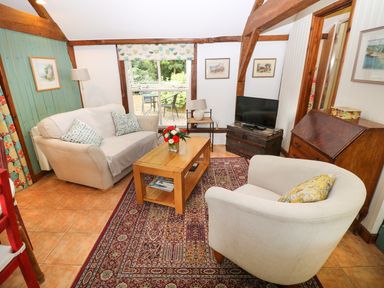 A living room with a sofa armchair wooden table and television at The Pottery in Urchfont near Devizes