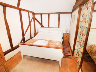 A bedroom with a double bed between two wooden nightstands and floral curtains at The Pottery in Urchfont near Devizes