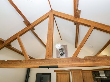 A view of wooden beams and light fixture in a living room at Yew Tree Cottage in Torver