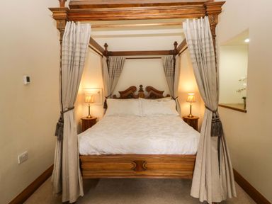 A four-poster bed with bedside lamps at Yew Tree Cottage in Torver