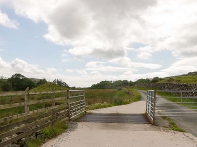 A gate and road in a grassy area at Yew Tree Cottage in Torver