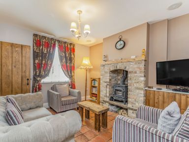 A living room with armchairs a sofa a wooden coffee table a brick fireplace and a television at Fisher Cottage in Hornsea