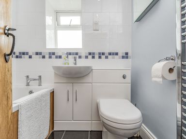 A bathroom with a bathtub sink toilet and a towel hanging on a wooden door at Fisher Cottage in Hornsea