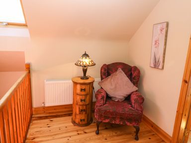 A seating area with a chair and lamp at Stone Cottage in Waterville, County Kerry