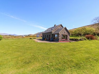 A stone house with garden and mountains in the background at Stone Cottage, Waterville, County Kerry
