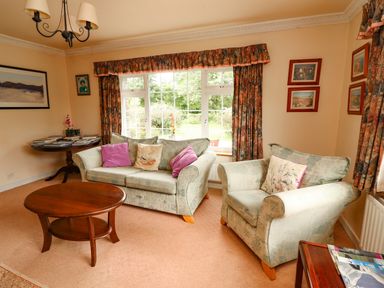 A living room with two sofas a round wooden coffee table and framed pictures on the wall at The Lodge in Churchtown near Beaufort County Kerry