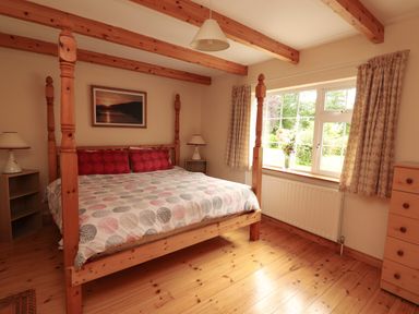 A bedroom with a wooden four-poster bed and bedside tables at The Lodge in Churchtown near Beaufort County Kerry
