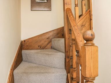 A carpeted wooden staircase with a wooden handrail in a hallway at Cairns Cottage Whitby