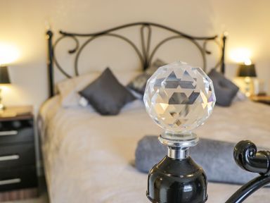 A bedroom with a bed with decorative pillows and bedside tables with lamps at Cairns Cottage in Whitby