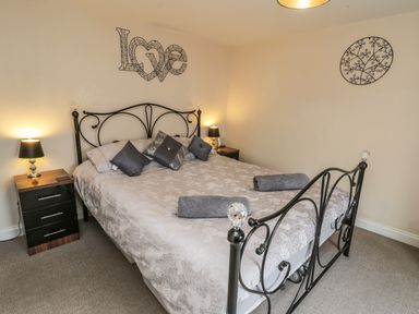 A bedroom with a metal framed bed bedside tables lamps and wall decorations at Cairns Cottage in Whitby