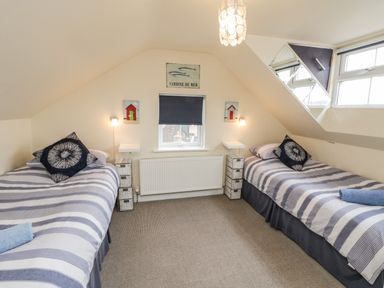 A bedroom with two single beds striped bedding and wall decorations at Cairns Cottage in Whitby