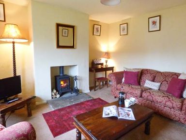 A living room with a fireplace wooden coffee table and patterned sofa at The White Cottage in Bridlington