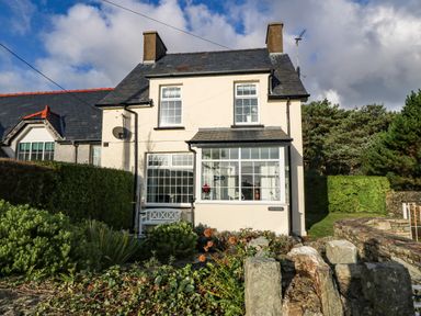 A two-story house with large windows and a garden with shrubs and rocks at Ty'r Ysgol in Morfa Bychan