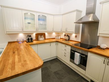 A kitchen with wooden countertops white cabinets a toaster a kettle and a stove at Ty'r Ysgol in Morfa Bychan