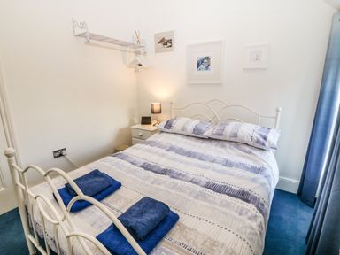 A bedroom with a metal bed frame bedside table lamp blue towels on bed at Ty'r Ysgol in Morfa Bychan