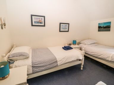 A bedroom with two single beds a bedside table with a lamp and framed pictures on the walls at Ty'r Ysgol in Morfa Bychan