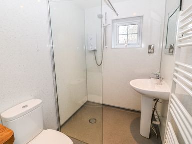 A bathroom with a toilet sink shower area and a small window at Ty'r Ysgol in Morfa Bychan
