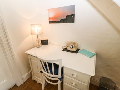 A white desk with a table lamp vintage rotary phone notebook and chair in a corner of a room at Ty'r Ysgol in Morfa Bychan