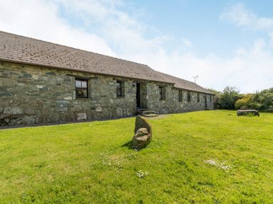 A stone cottage with small windows and a grass lawn in front at Foxglove in Newport Pembrokeshire