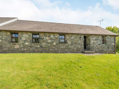 A stone cottage with four windows and a door on a grassy lawn at Foxglove in Newport Pembrokeshire