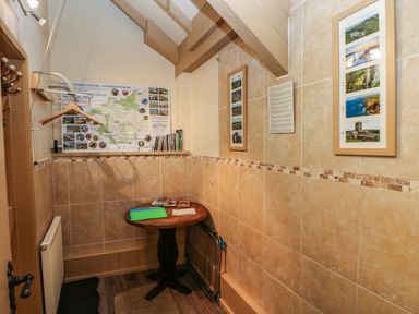 A small room with a round wooden table hanging hooks maps and framed pictures on tile walls at Foxglove in Newport Pembrokeshire