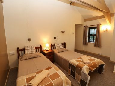 A bedroom with two single beds each with a pillow and rolled towel and a bedside table with a lamp between them at Foxglove Newport Pembrokeshire