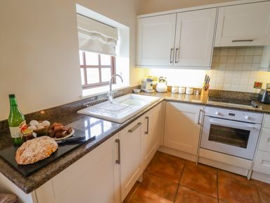 A kitchen with a window above a sink and countertop with bread eggs and brownies at Dairy Barn in Pershore