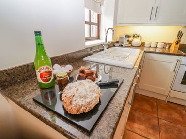 A kitchen countertop with apple juice bottle eggs jar of jam baked bread and brownies near a sink at Dairy Barn in Pershore