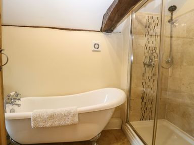 A bathroom with a clawfoot bathtub and a glass-enclosed shower at The Barn in Saham Hills near Swaffham
