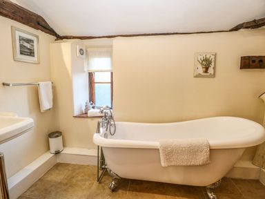 A bathroom with a freestanding bathtub a sink a towel rail and a small window at The Barn in Saham Hills near Swaffham