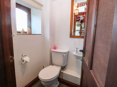 A small bathroom with a toilet sink mirror window and two small vases on the window sill at The Barn in Saham Hills near Swaffham