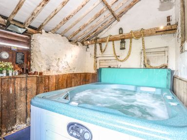 A hot tub in a rustic room with wooden beams and white plaster walls at The Barn Saham Hills near Swaffham