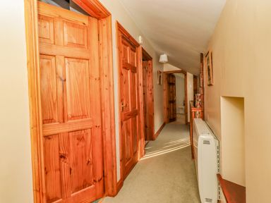 A hallway with wooden doors carpeted floor and a wall heater at Hadrian's View Banks near Brampton