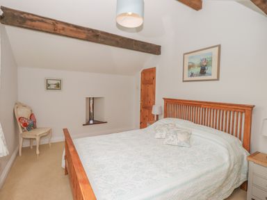 A bedroom with a wooden bed two bedside tables and a chair with a butterfly cushion at Hadrians View Banks near Brampton