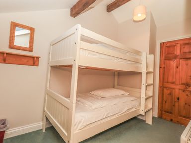 A bedroom with a white bunk bed a wooden door a wicker framed mirror and a pendant light at Hadrians View in Banks near Brampton