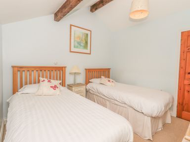 A bedroom with two single beds a bedside table with a lamp a framed picture on the wall and a wooden door at Hadrians View Banks near Brampton