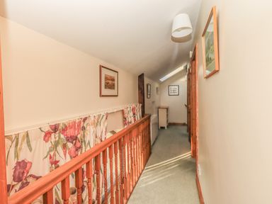 A hallway with wooden railing and floral curtains along the side at Hadrians View Banks near Brampton