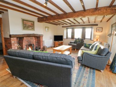 A living room with a brick fireplace gray sofas a wooden coffee table and a television at Hadrians View in Banks near Brampton