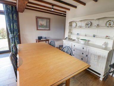 A dining room with a wooden table black chairs a white cabinet and a small table with a radio at Hadrians View Banks near Brampton