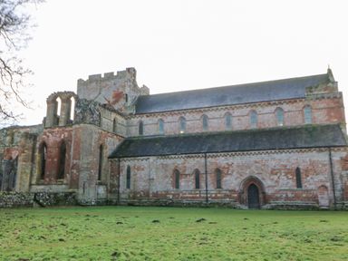 A large stone building with arched windows and a tower on a grassy area at Hadrians View Banks near Brampton