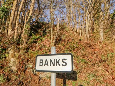A roadside sign with the word Banks against a background of leafless trees and vegetation at Hadrians View in Banks near Brampton