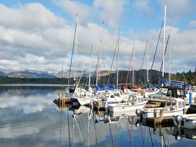 A marina with sailboats docked on calm water with hills in the background at Top Lodge 4 Skiptory Howe White Cross Bay near Troutbeck Bridge