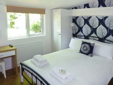 A bedroom with a bed with white linens and towels a desk and a window at Top Lodge 4 Skiptory Howe White Cross Bay near Troutbeck Bridge